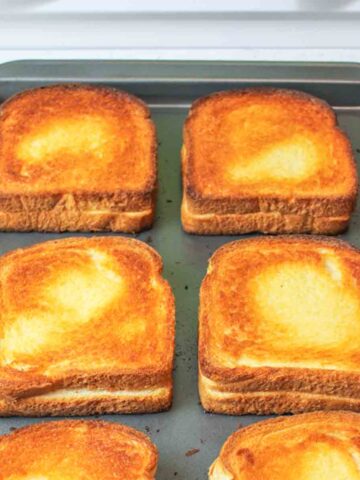 close up of grilled cheese sandwiches on a baking sheet