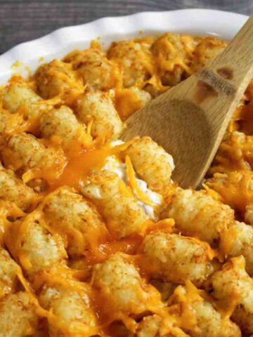 a wooden spoon scooping into a tater tot casserole hotdish.