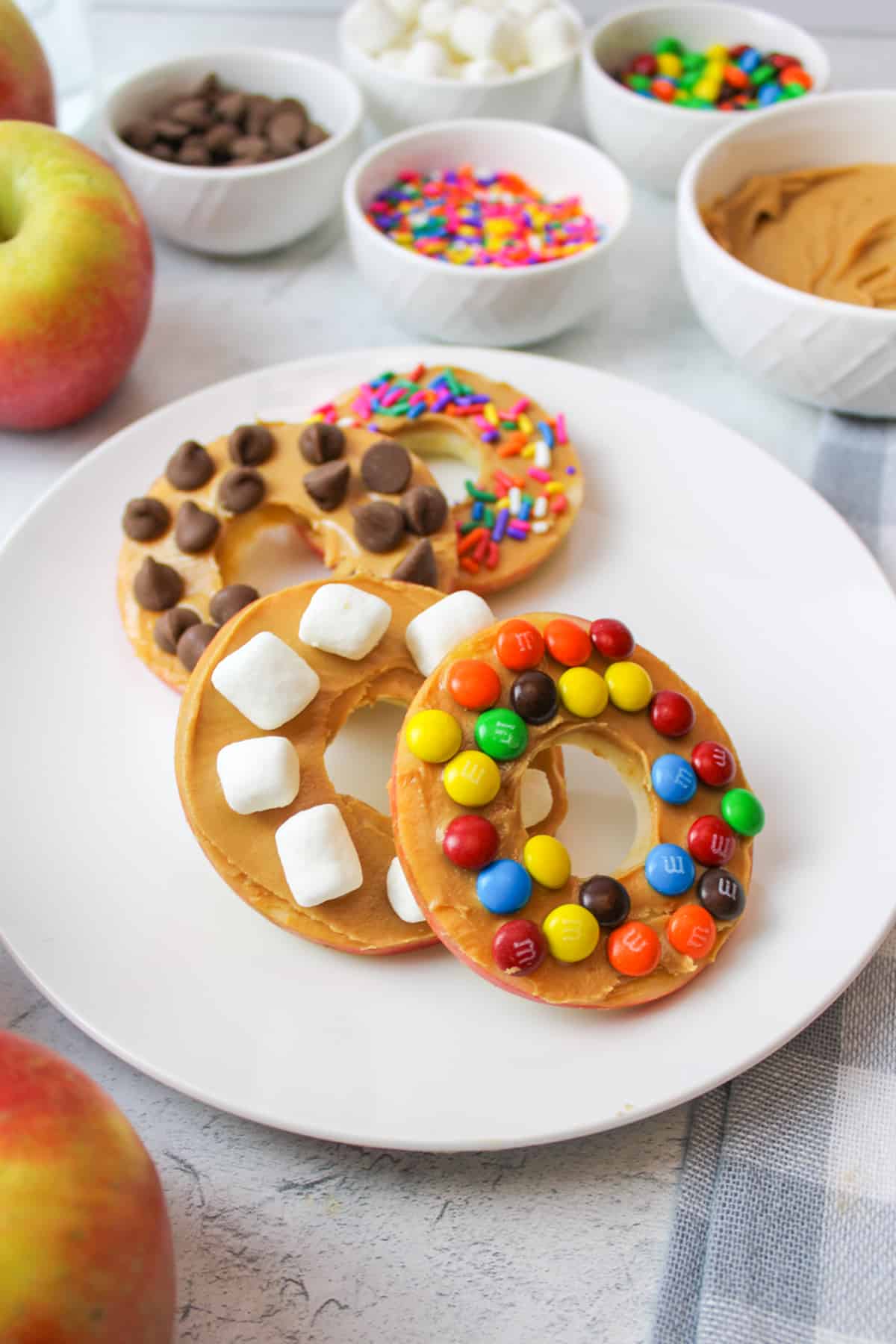 4 apple donuts on a plate leaning on one another in a curved line.