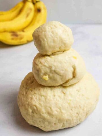 three balls of banana playdough stacked like a small snowman.