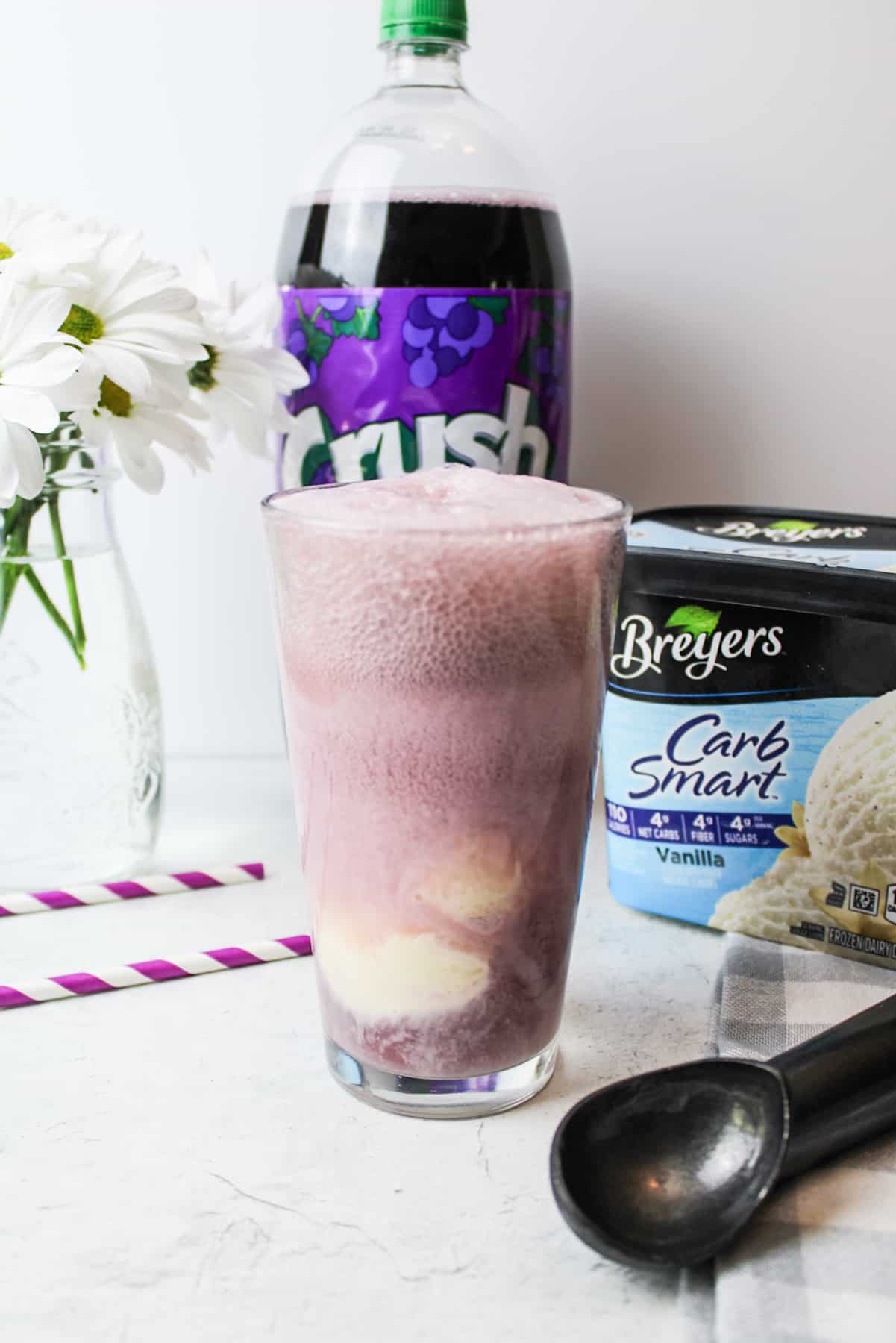 Grape soda in glass with vanilla ice cream, ice cream scooper aside.