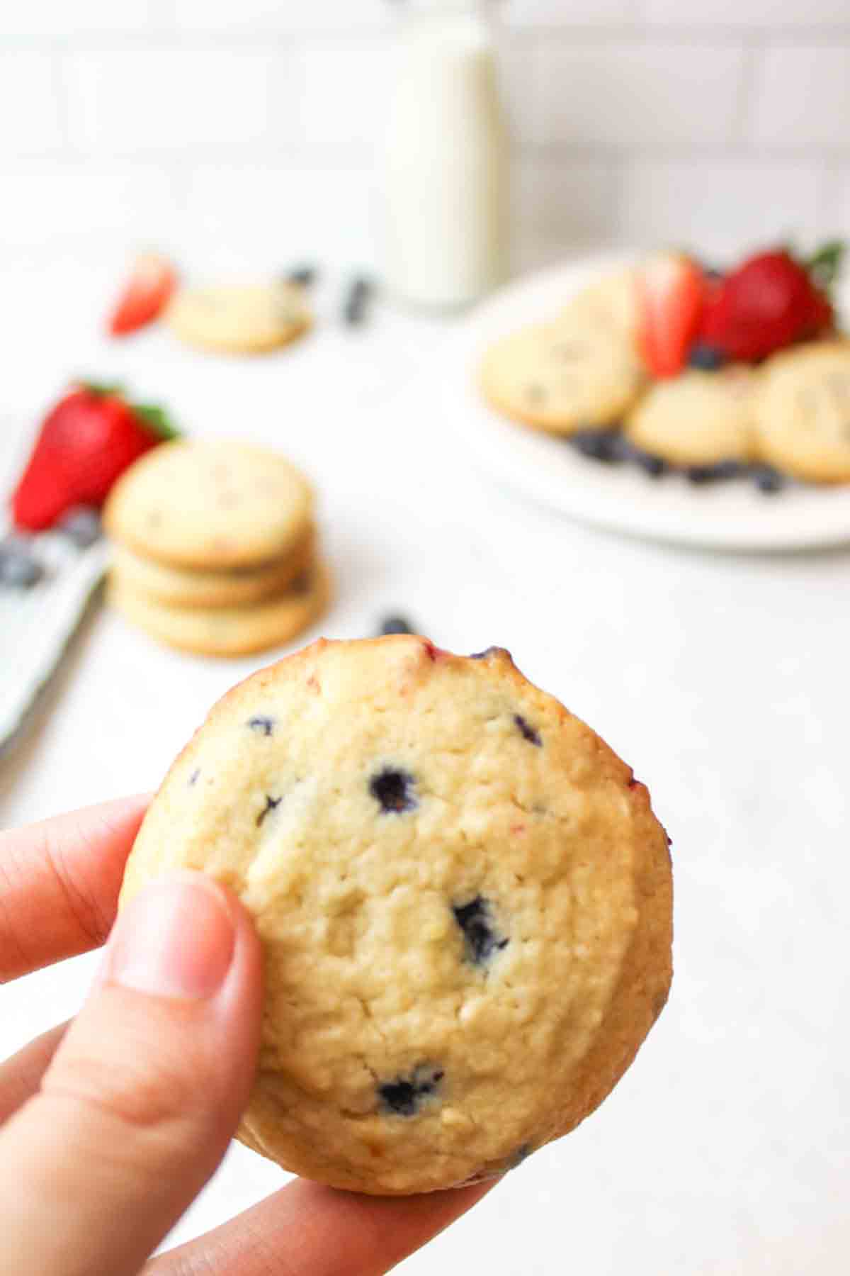 a hand holding up a triple berry muffin mix cookie