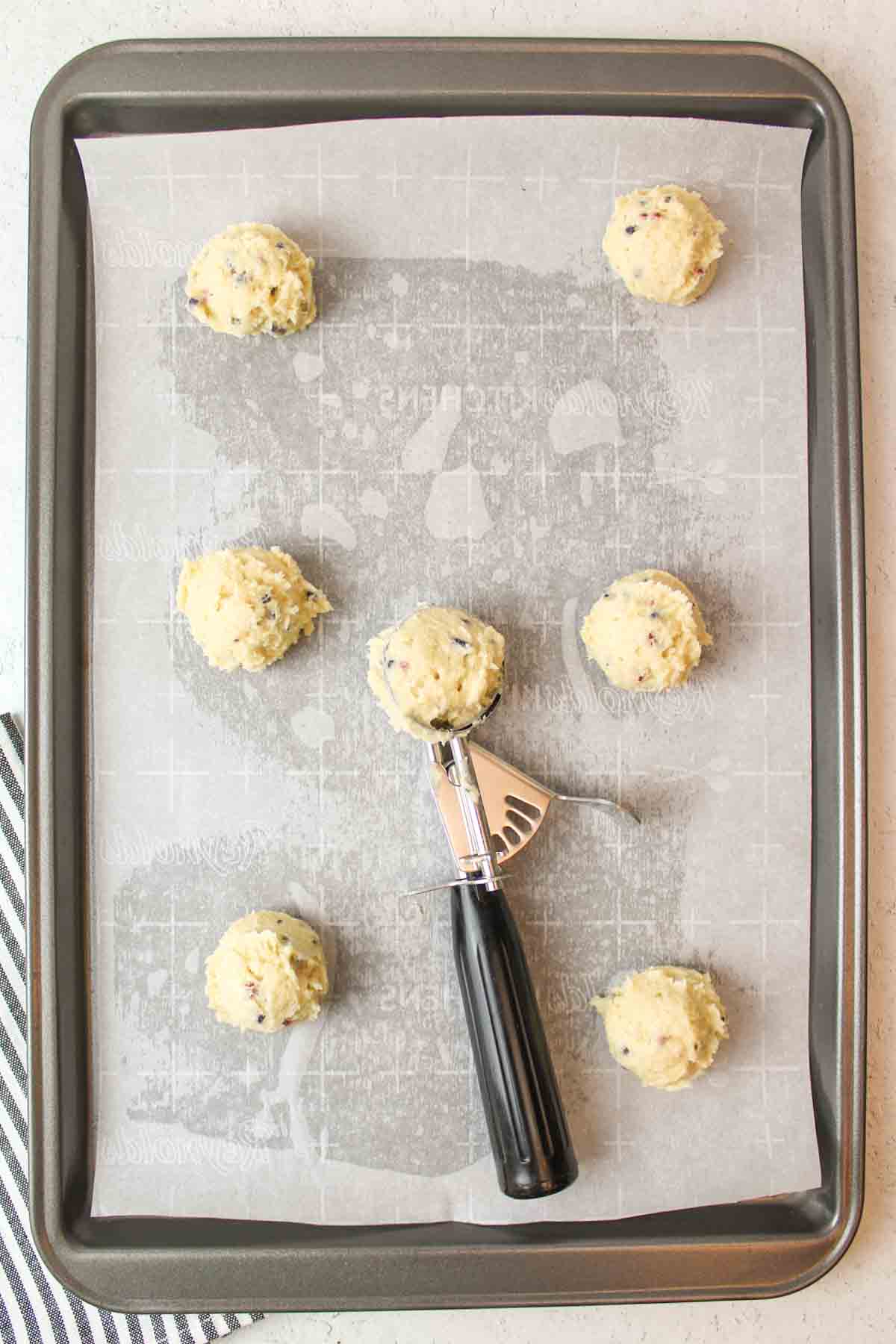 parchment paper lined baking sheet with scoops of raw cookie dough on it