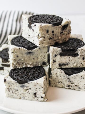 several squares of oreo fudge on a plate with a striped towel in background.
