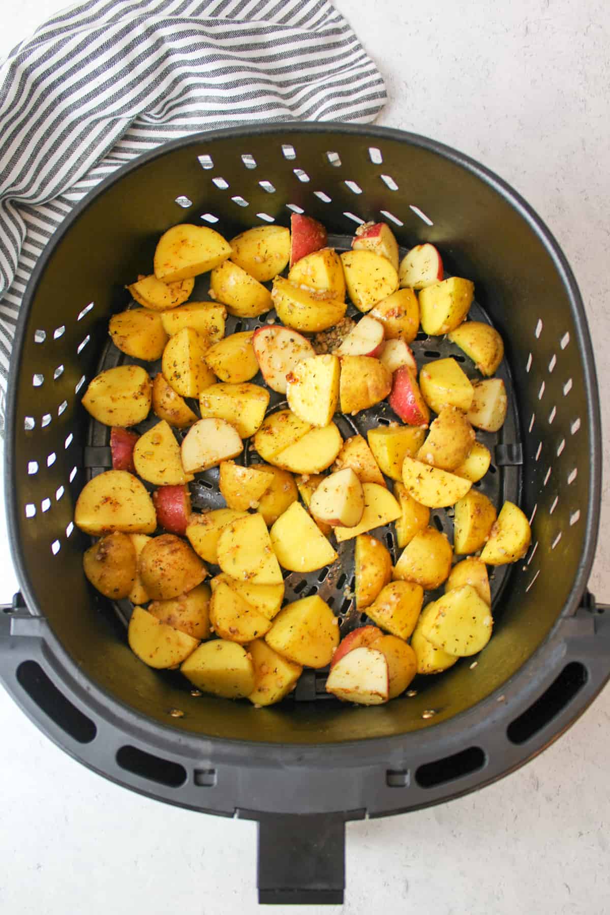 seasoned potatoes in an air fryer basket.