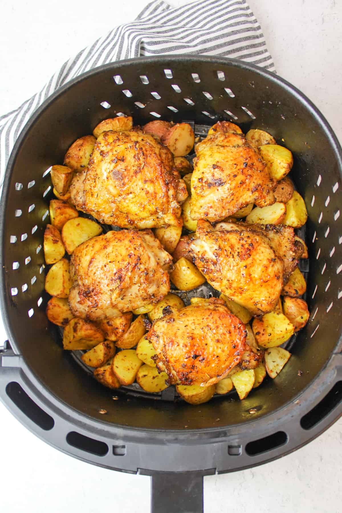 air fried chicken thighs and potatoes in air fryer basket