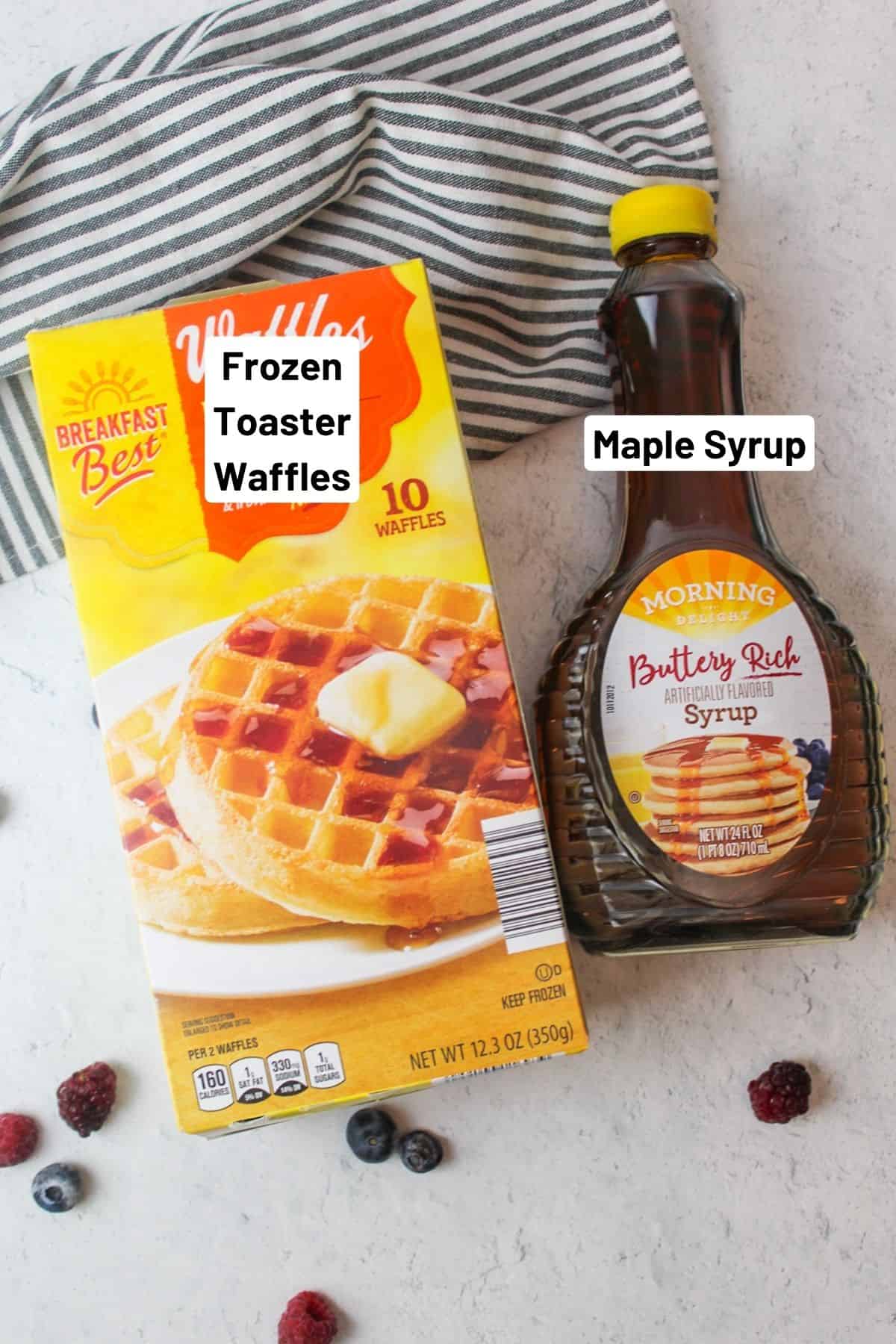 box of frozen waffles next to bottle of syrup and scattered berries around them.