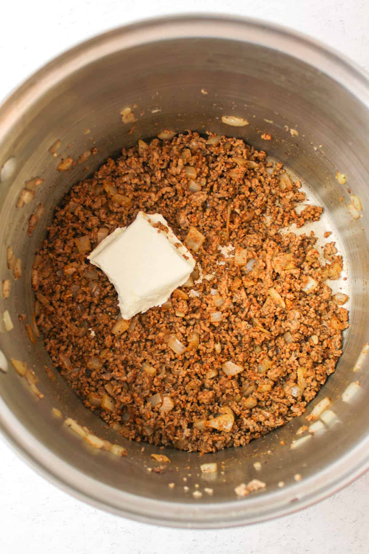 added cream cheese to a seasoned ground beef and onion mixture in a pot