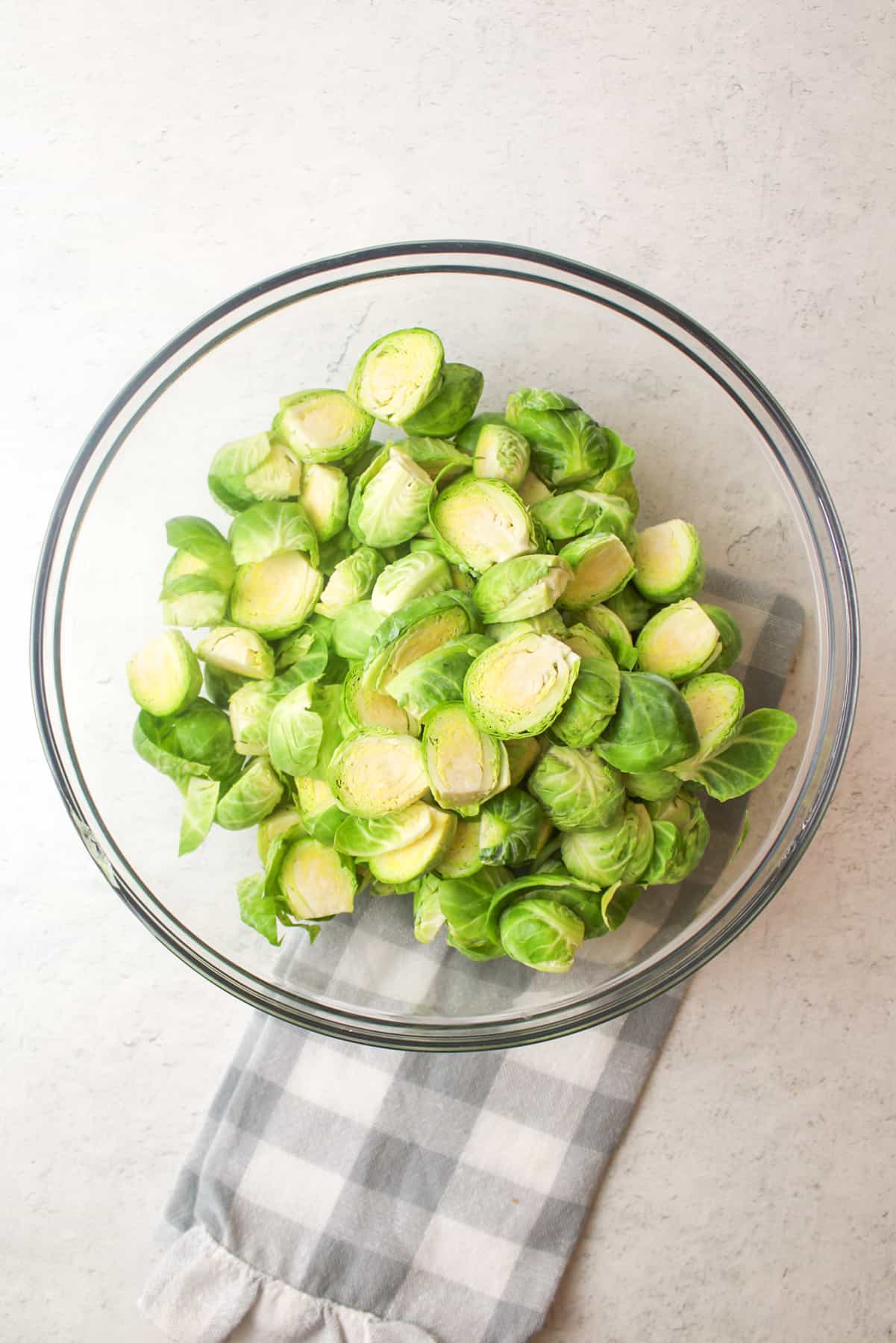 haled brussel sprouts in a glass bowl on a kitchen towel