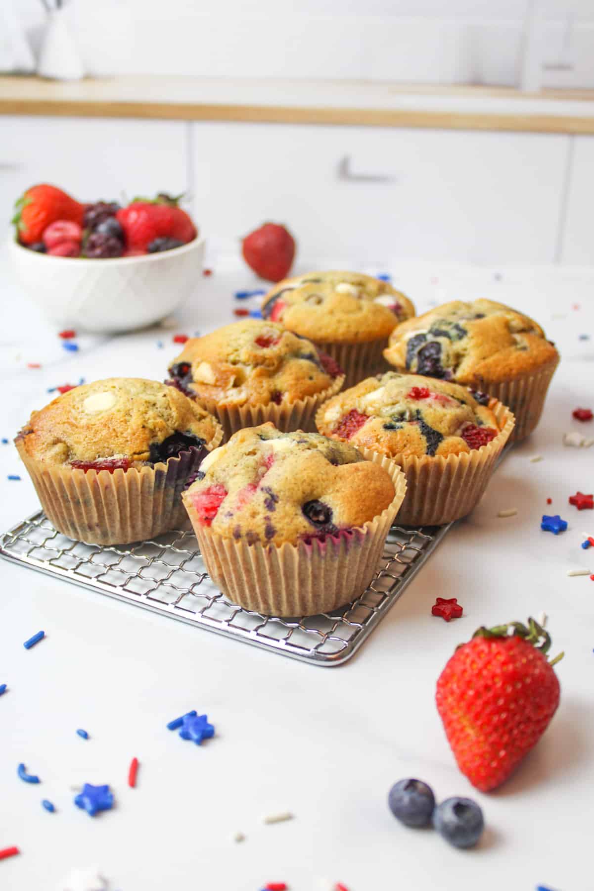 muffins with strawerries and blueberries inside on a wire rack.