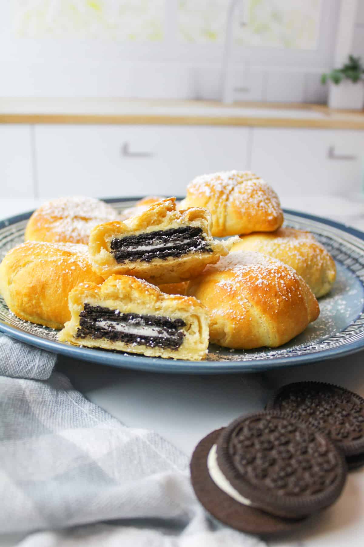 Air-fried Oreos dusted with powdered sugar on a blue plate, with additional Oreos nearby.