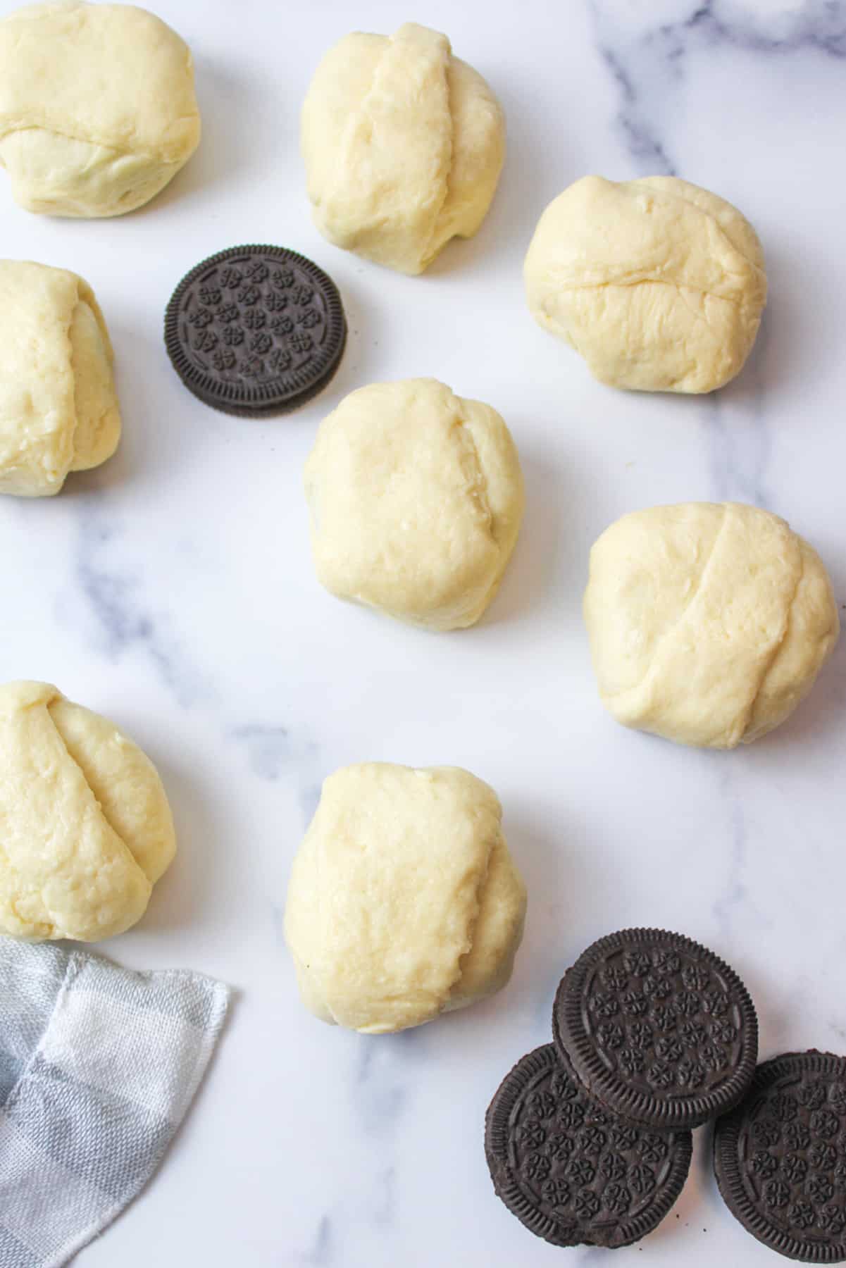 oreo cookies scattered around a bunch of crescent roll dough covered oreo cookies.