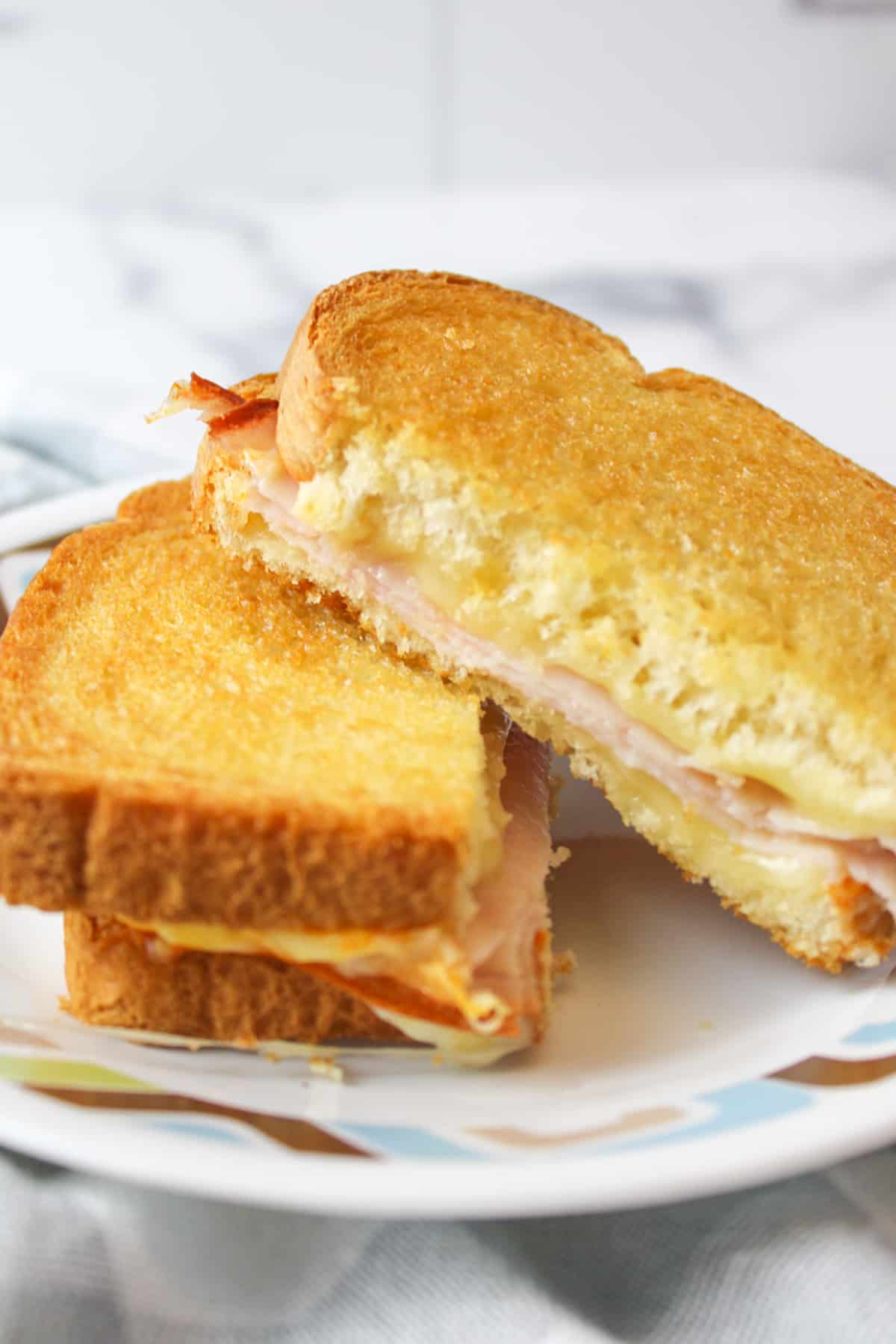 two angle stacked halves of an air fryer turkey sandwich with cheese.