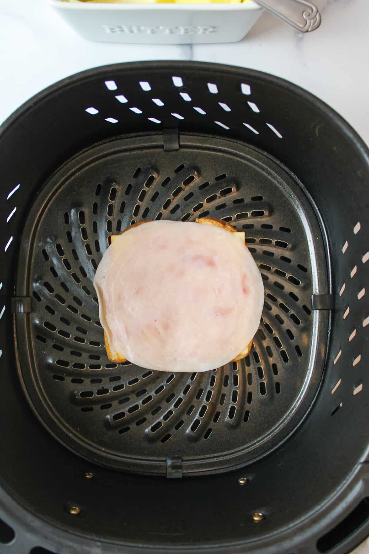 cheese and meat on bread in an air fryer basket.