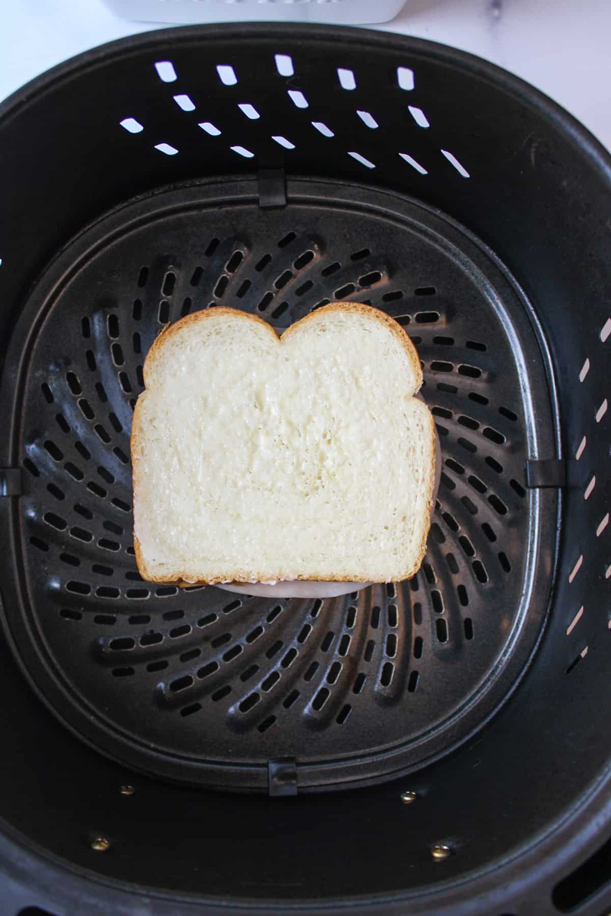 turkey and cheese sandwich in an air fryer basket.