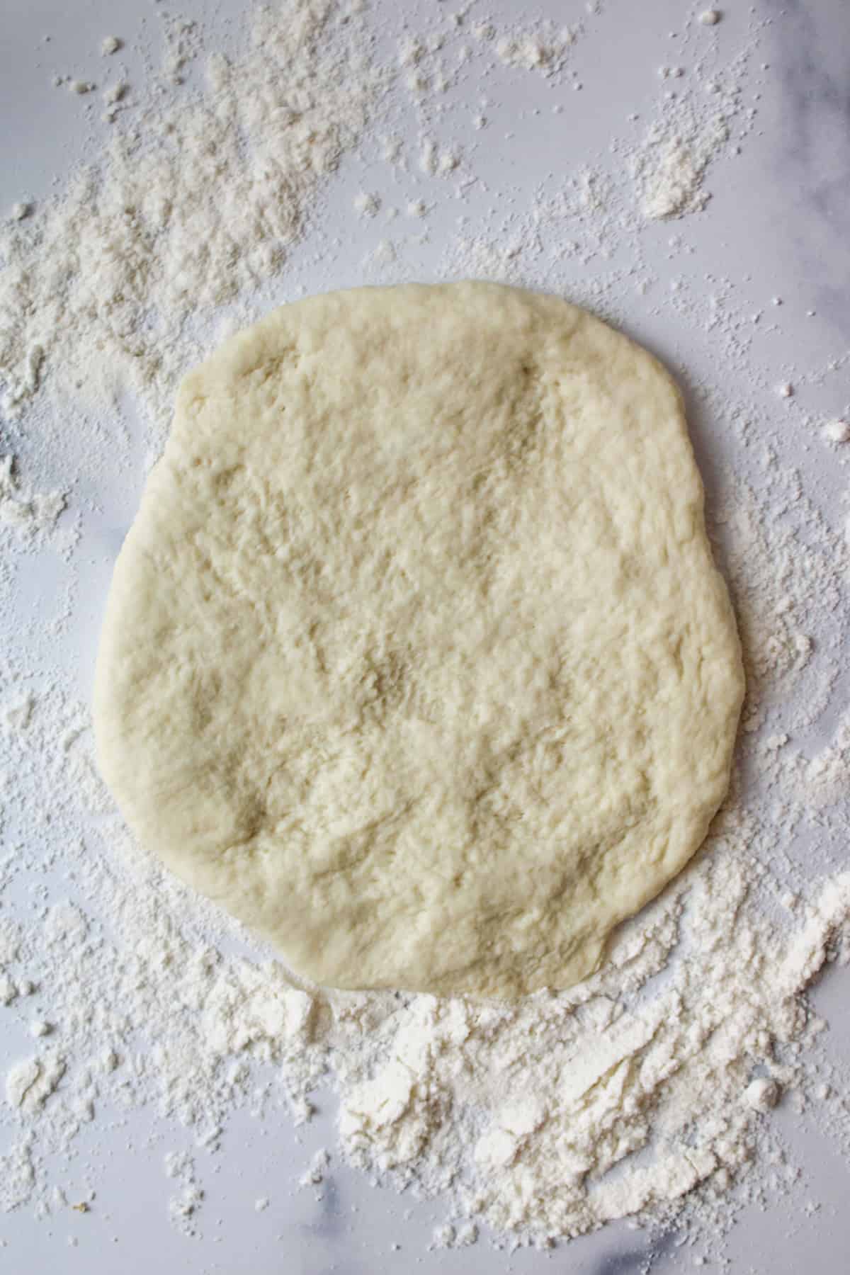 flattened dough on a floured surface