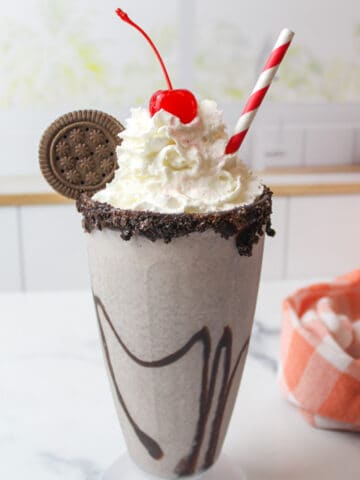 an oreo milkshake topped with whipped cream and and a cherry.