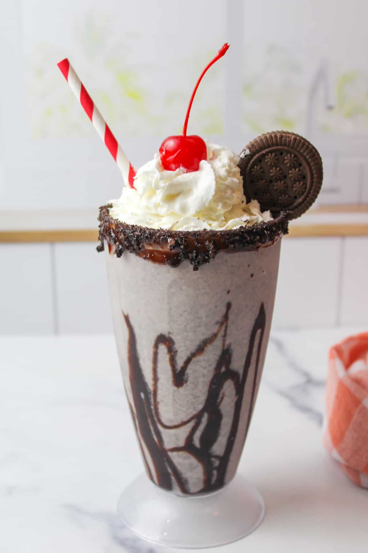 garnished cookies and cream milkshake in a chocolate drizzled milkshake glass.