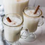 two garnished glasses full of ice col horchata with a cinnamon stick inside