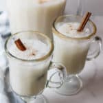 two garnished glasses full of ice col horchata with a cinnamon stick inside.