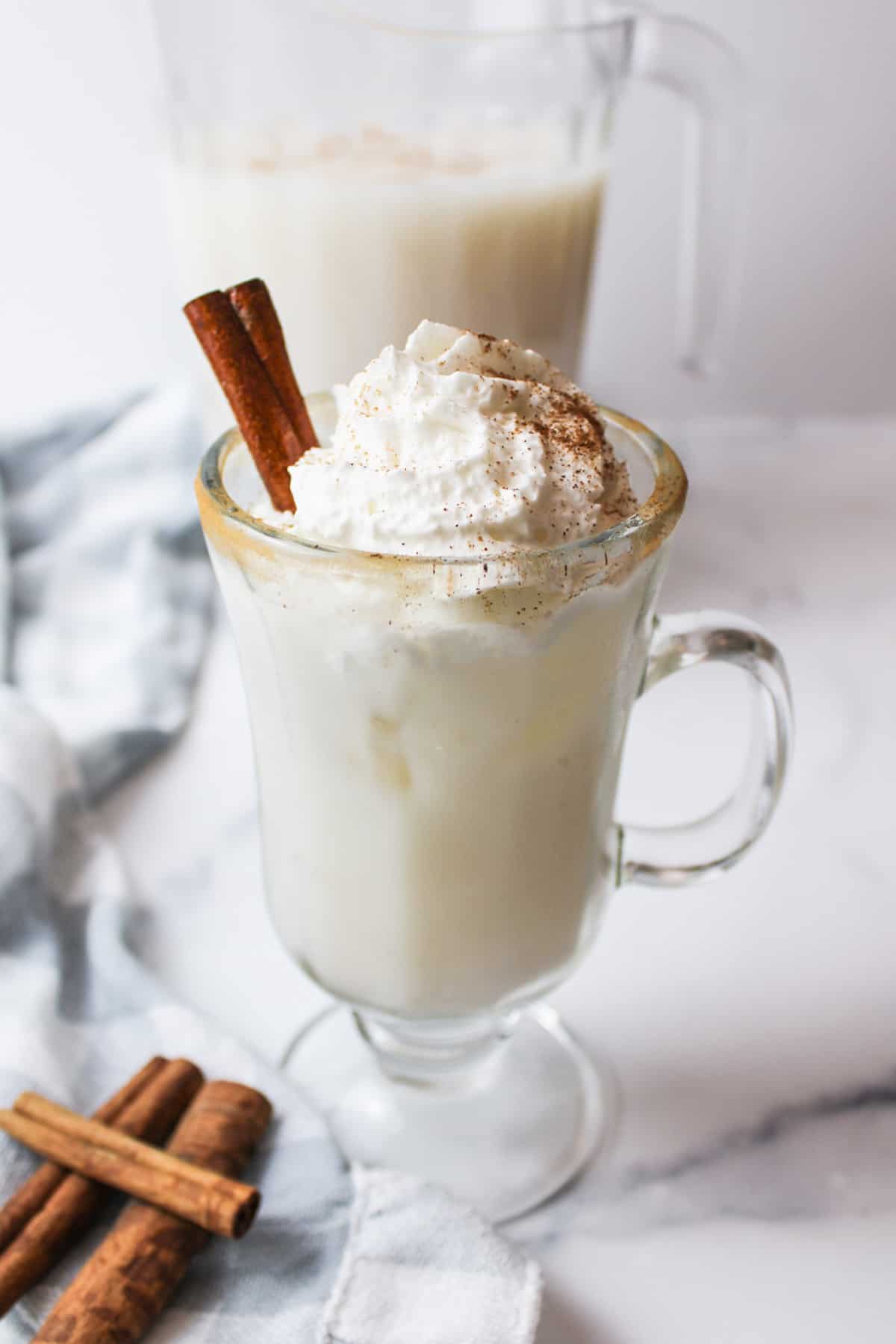 a glass of horchata topped with whipped cream and cinnamon.