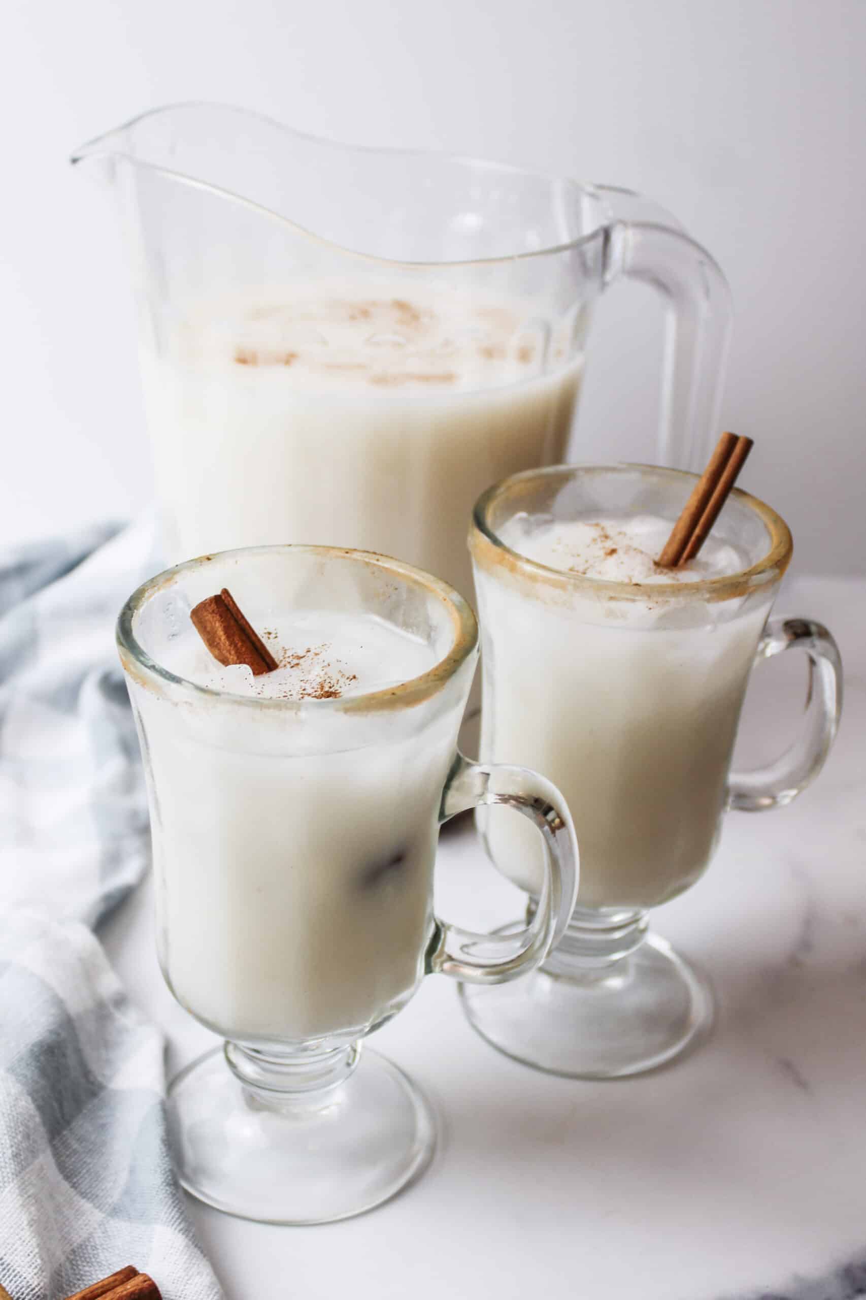 two glasses of cinnamon horchata in front of a pitcher.