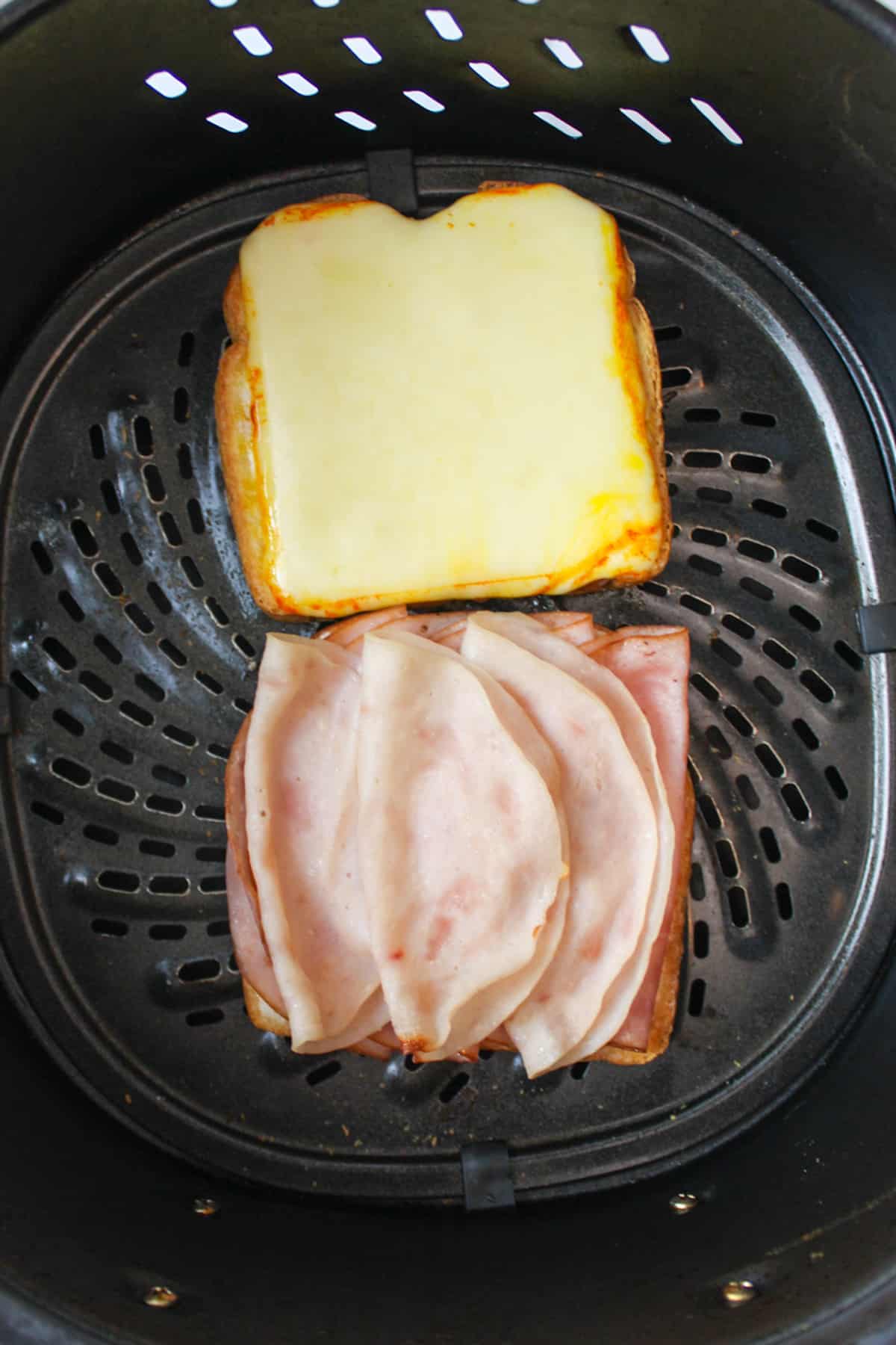 toasted meat and cheese on bread in air fryer basket