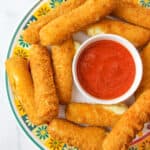 upclose aerial view of mozzarella sticks and a bowl of red marinara sauce