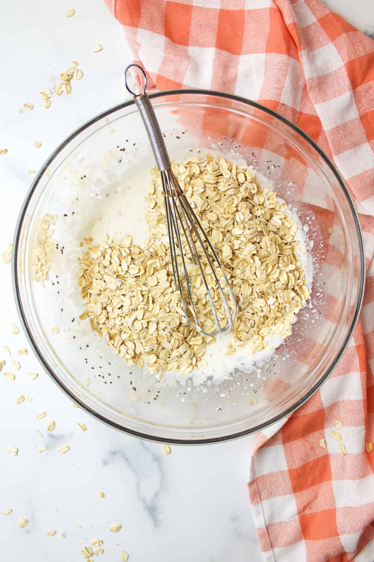 oats on top of wet ingredients in a bowl for overnight oats.