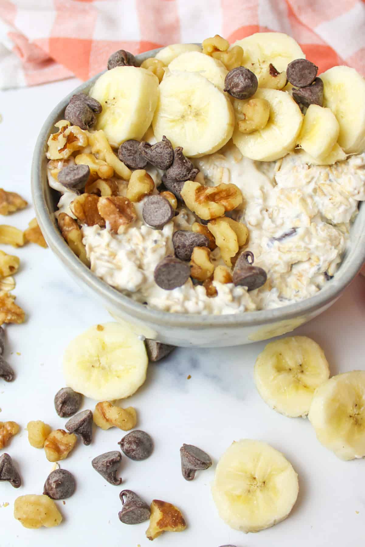 Chunky monkey oats in bowl, topped with walnuts, chocolate chips, banana.