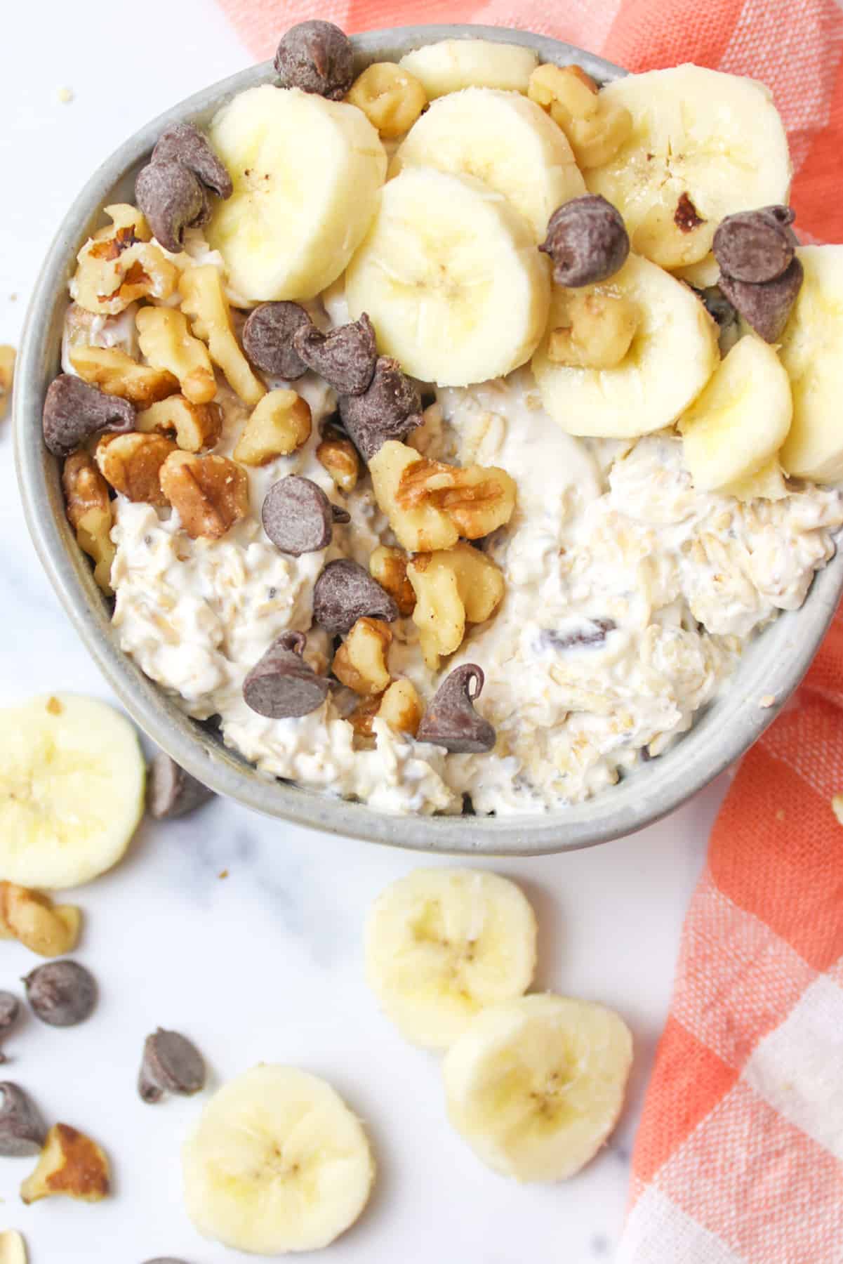 chunky monkey banana overnight oats in a bowl loaded with with toppings.