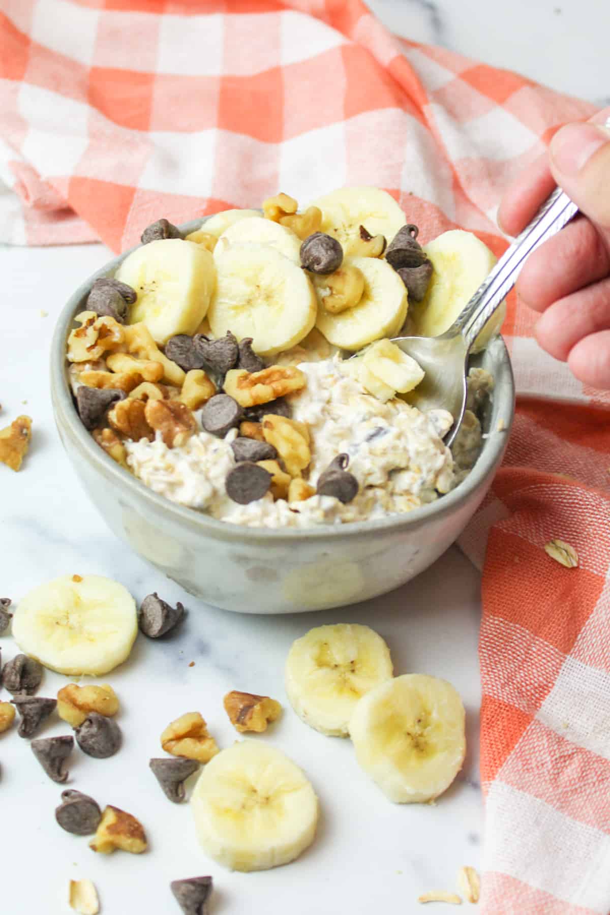 a spoon dipping into a bowl of chunky monkey flavored oats.