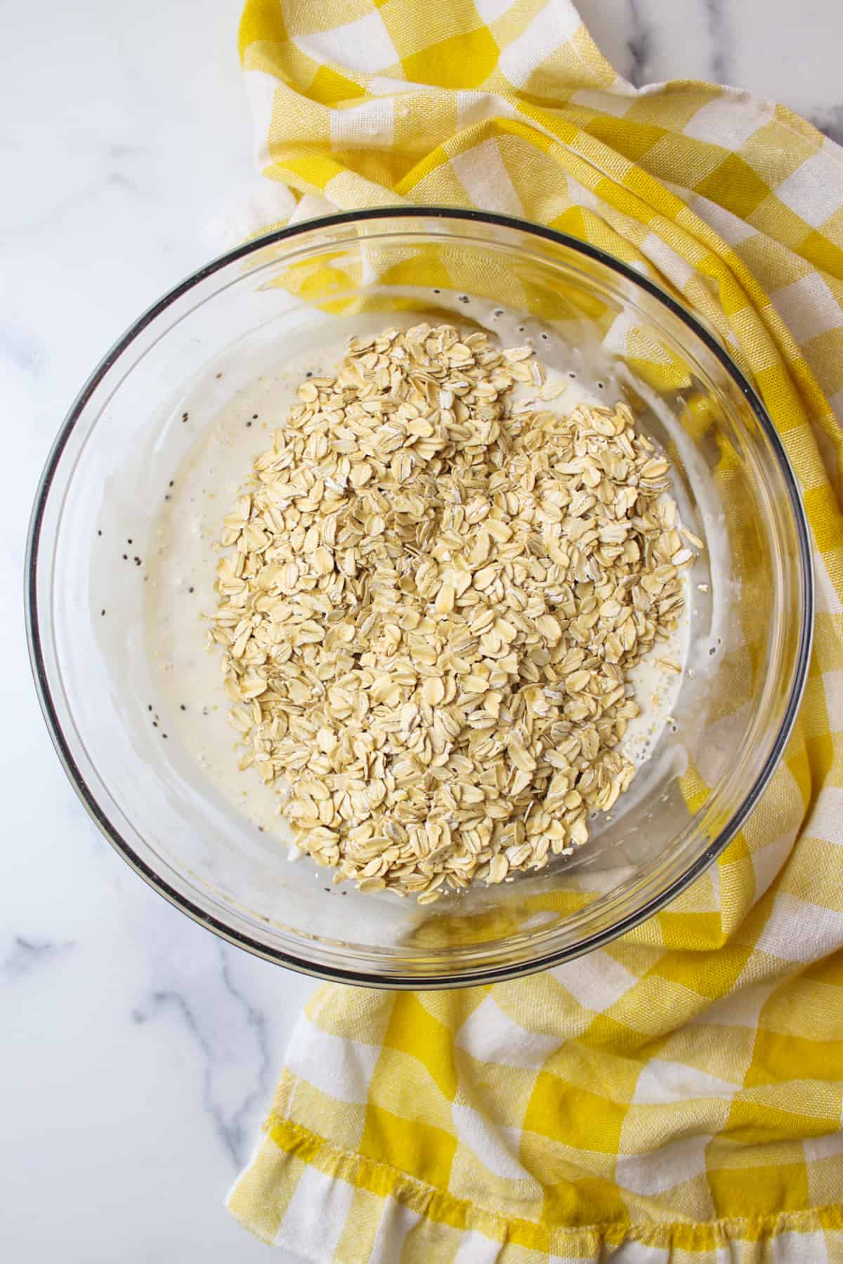 oats on top of wet ingredients in a bowl for overnight oats.