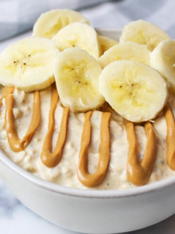 peanut butter drizzled on top of overnight oats with banana slices on top.