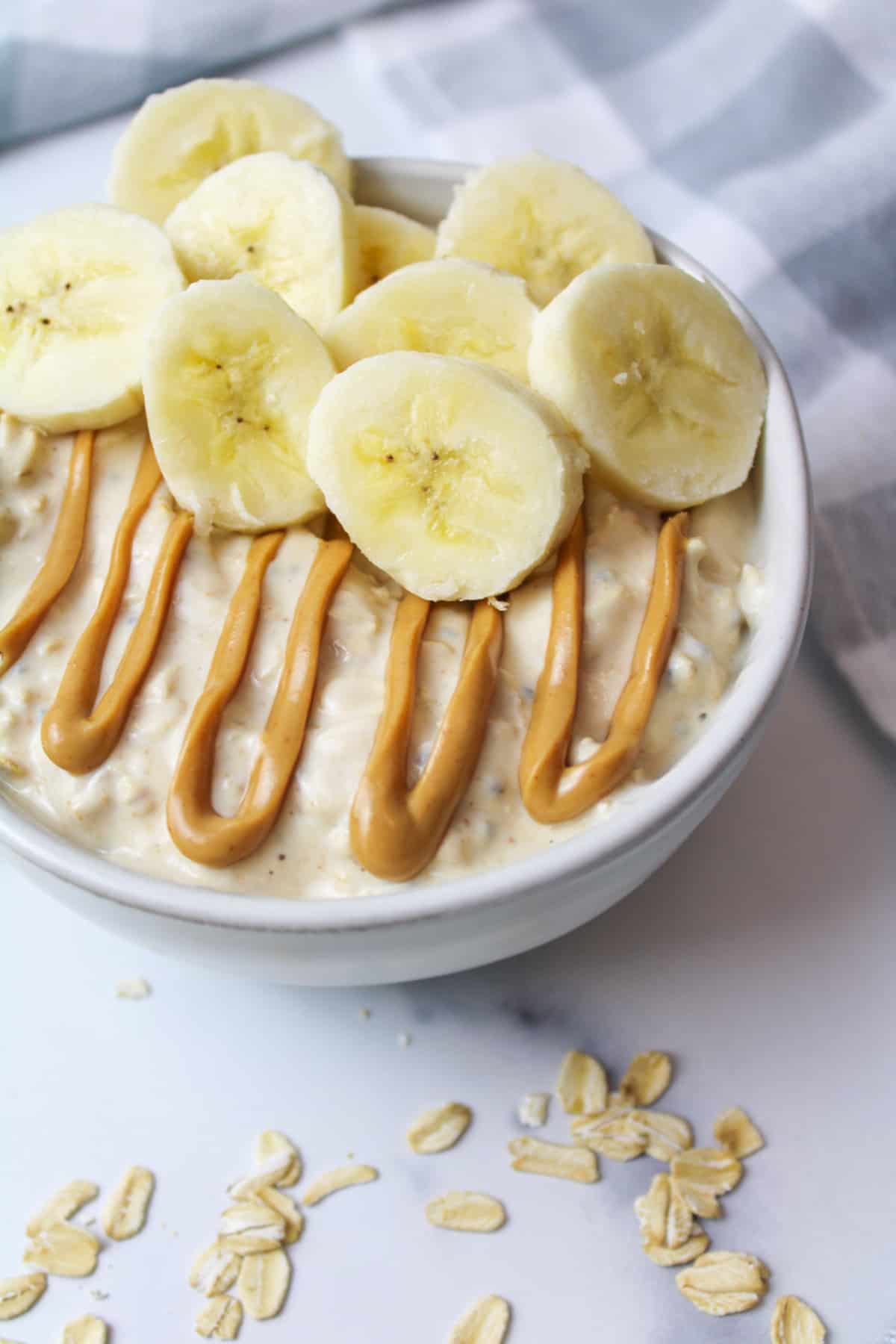 peanut butter and banana overnight oats in a bowl with scattered oats around it