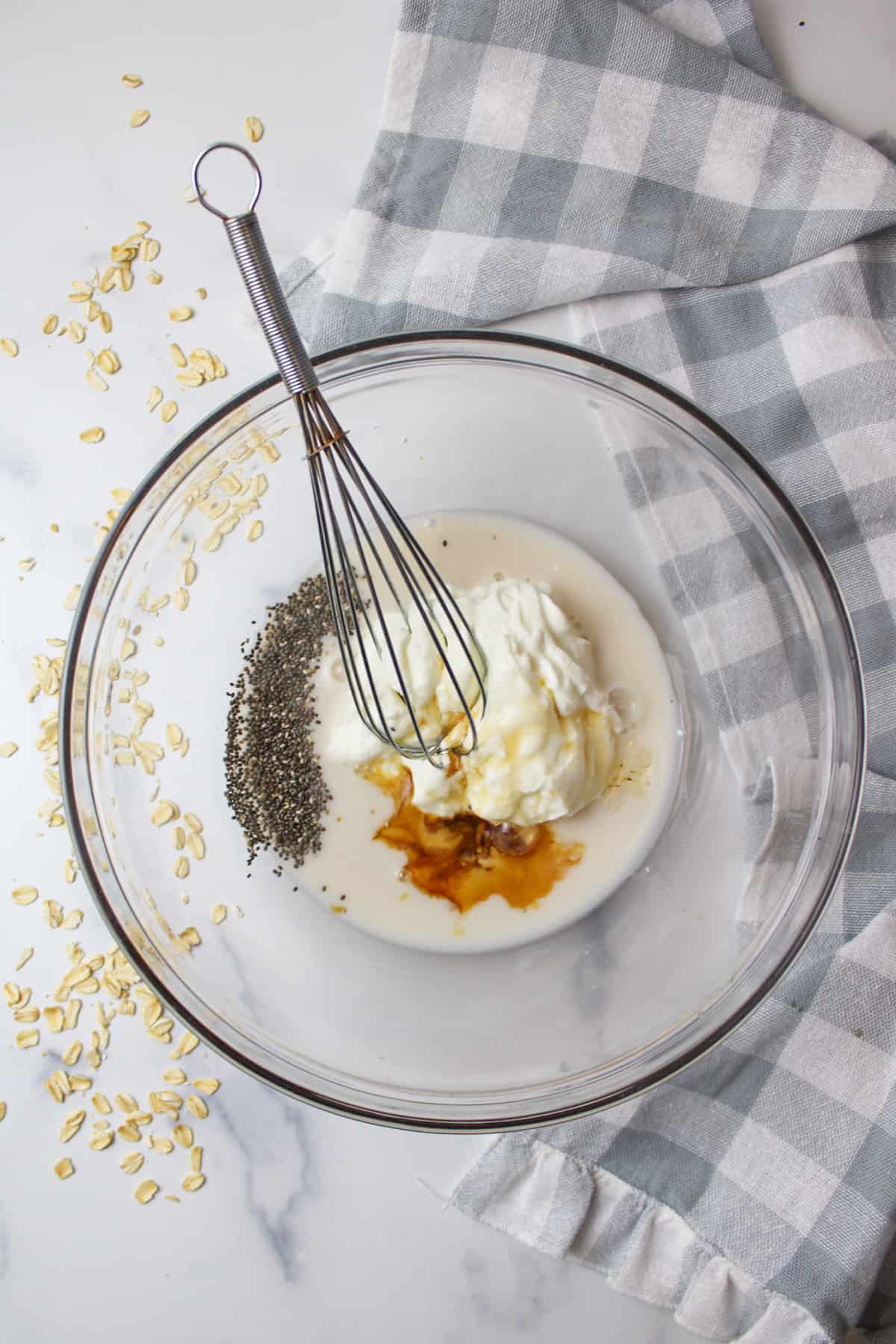 a mixing bowl with a whisk, greek yogurt, maple syrup, chia seeds and vanilla inside