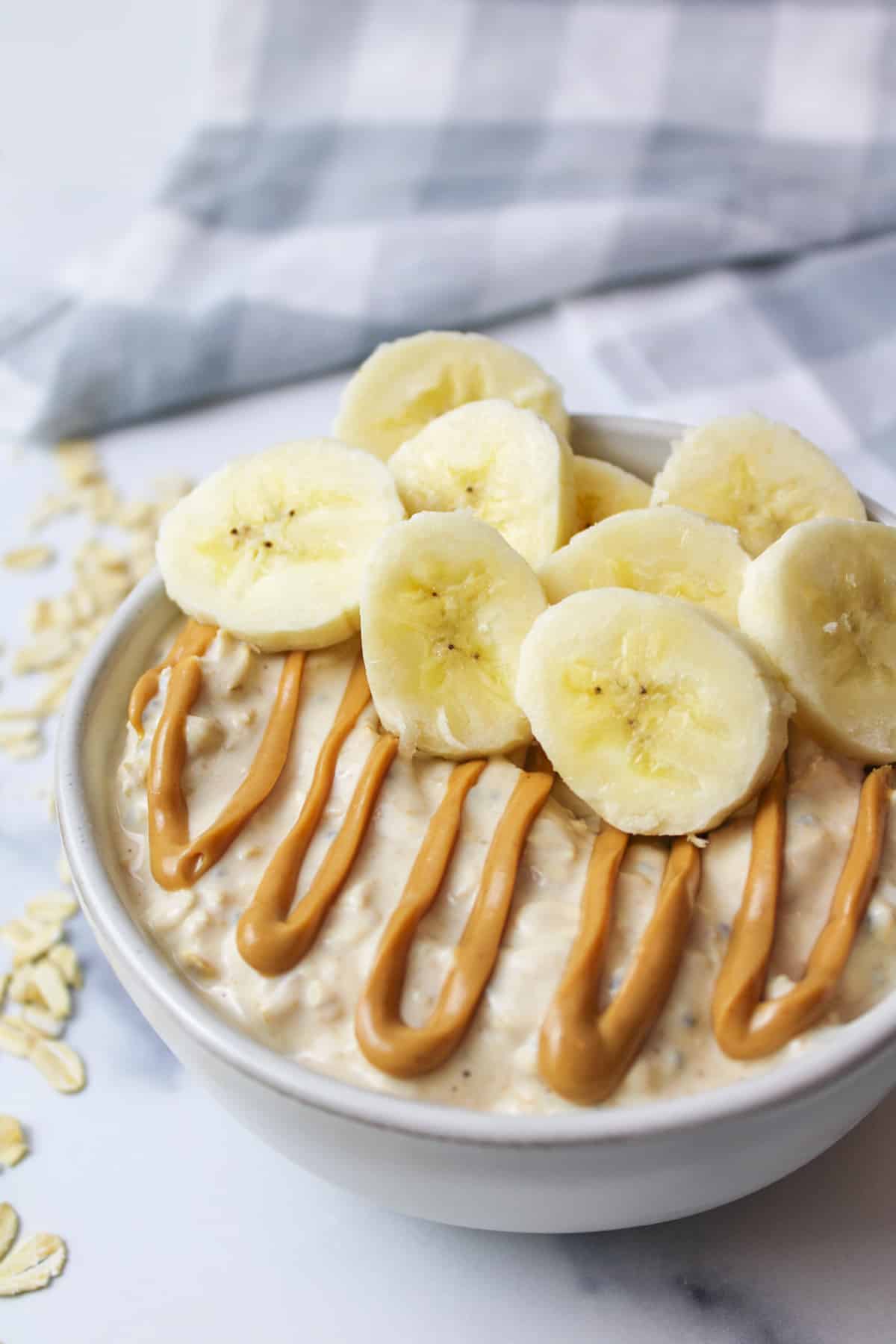 peanut butter and banana slices on overnight oats in a serving bowl.