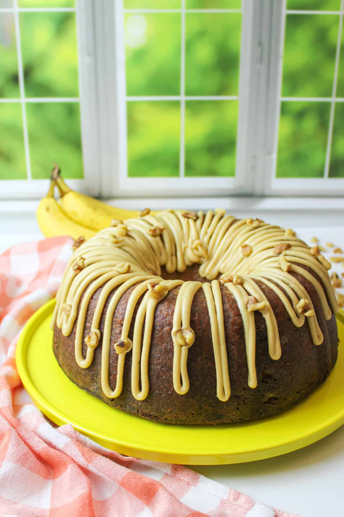 a banana pound cake with frosting on a yellow cake plate.