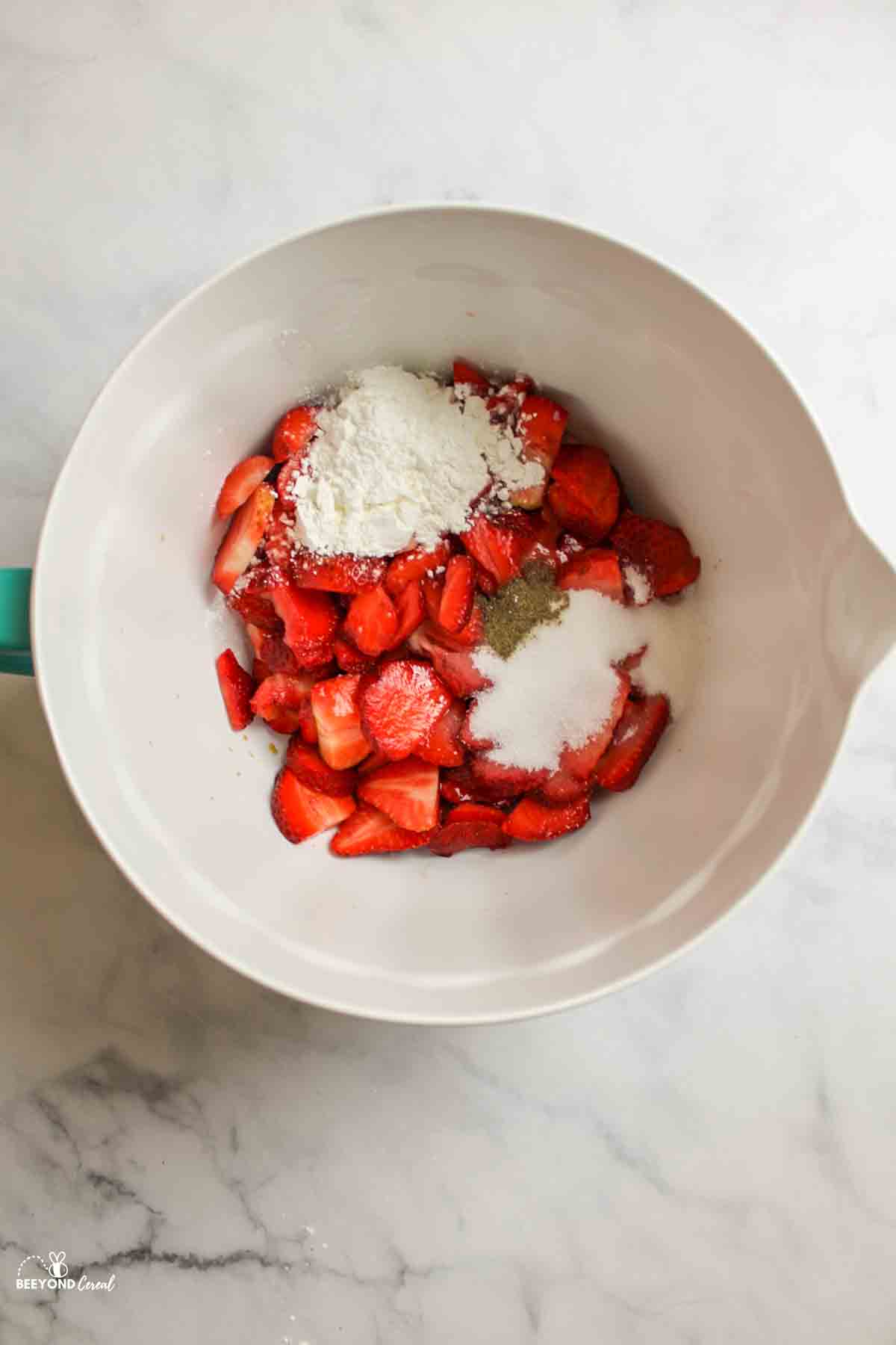 strawberries in a mixing bowl with black pepper flour and sugar.