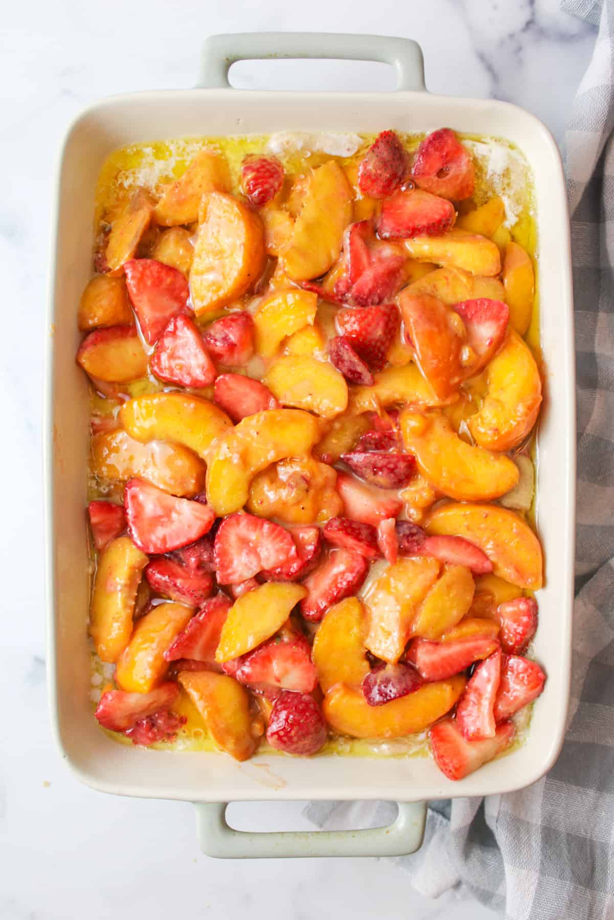 strawberry and peach mixture on top of cobbler topping in a baking dish