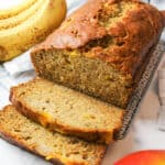 a sliced loaf of mango banana bread with bananas in background