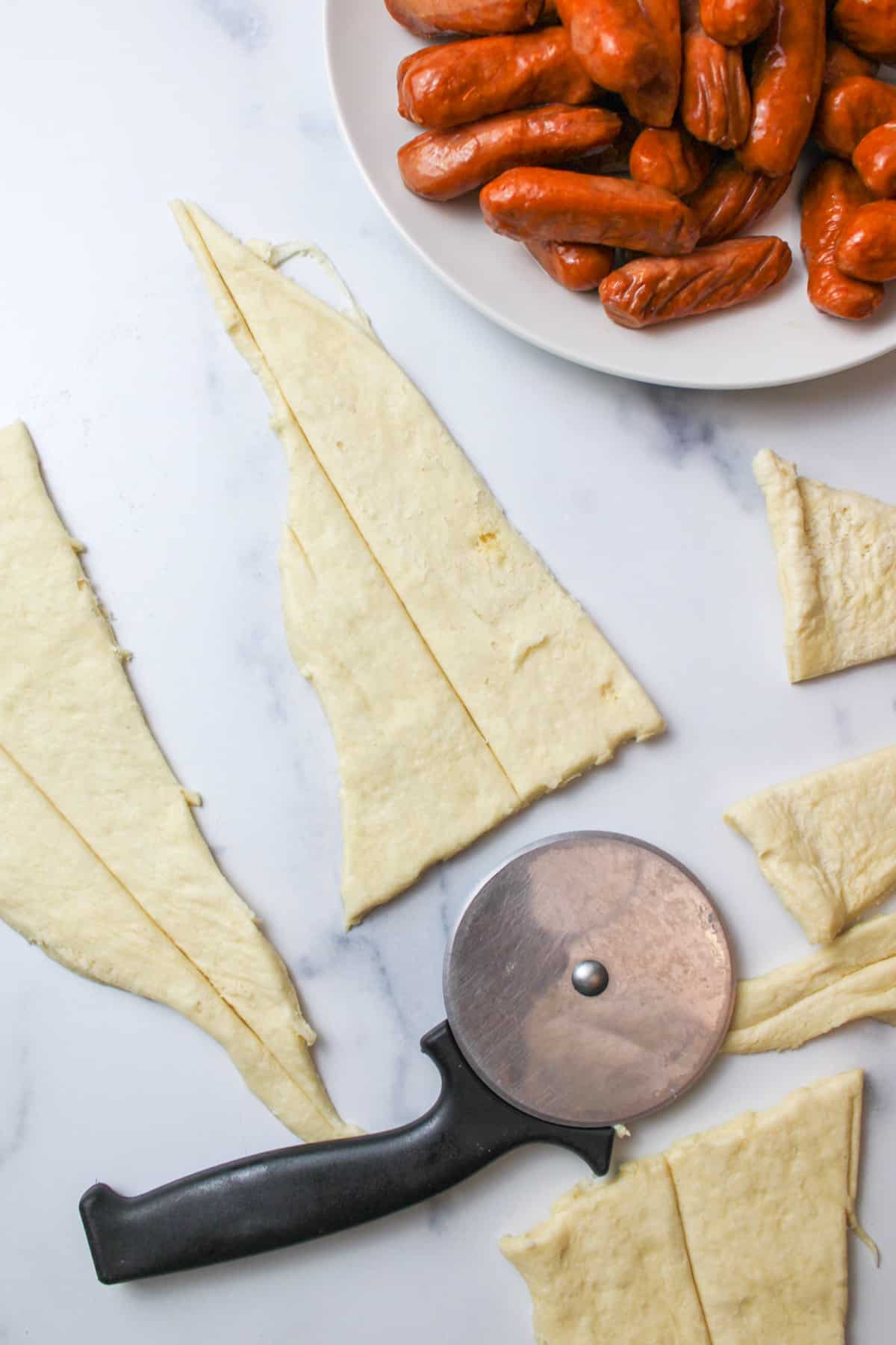 pizza cutter next to sliced crescent roll triangle