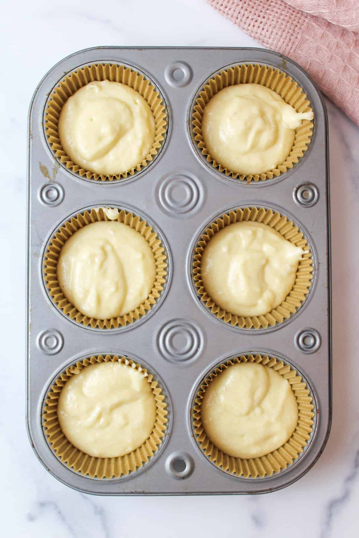 6 portioned vanilla muffins in a lined muffin pan