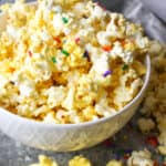 a bowl of almond bark popcorn with sprinkles.