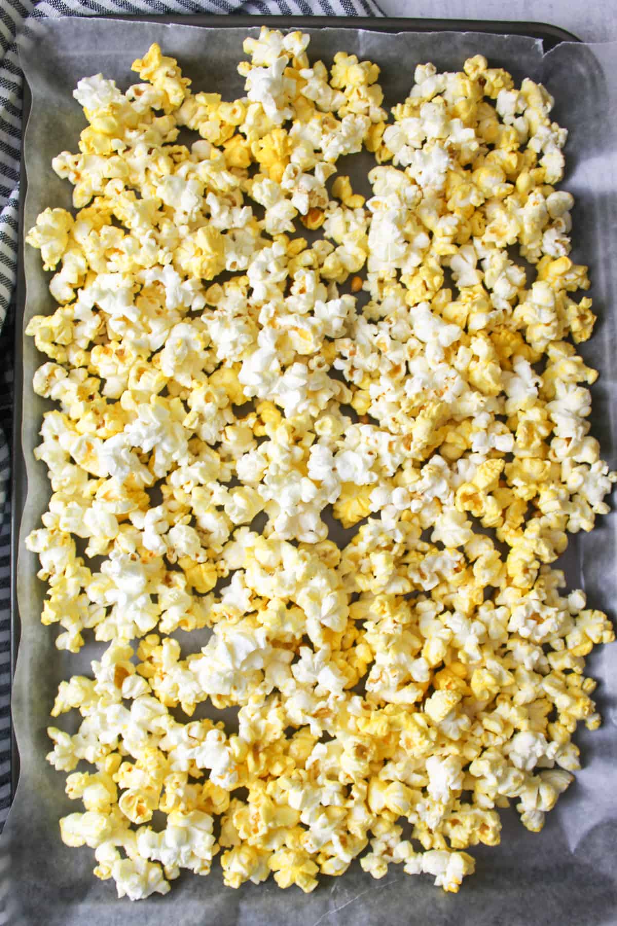 popcorn spread out on wax paper lined baking sheet.