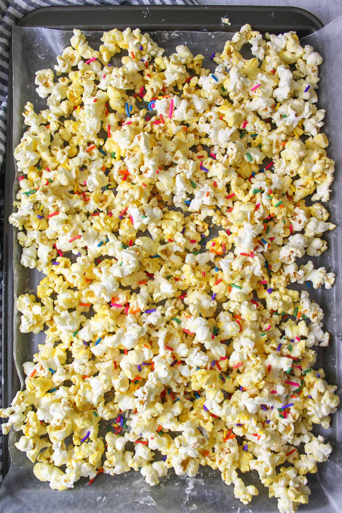 sprinkles on top of almond bark coated popcorn on wax paper covered baking sheet.