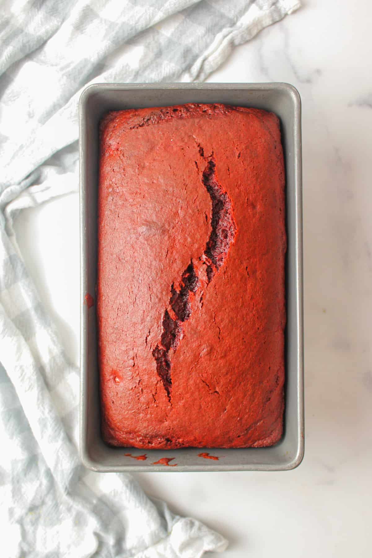 baked red velvet banana bread with a crack down the center in a bread loaf pan and