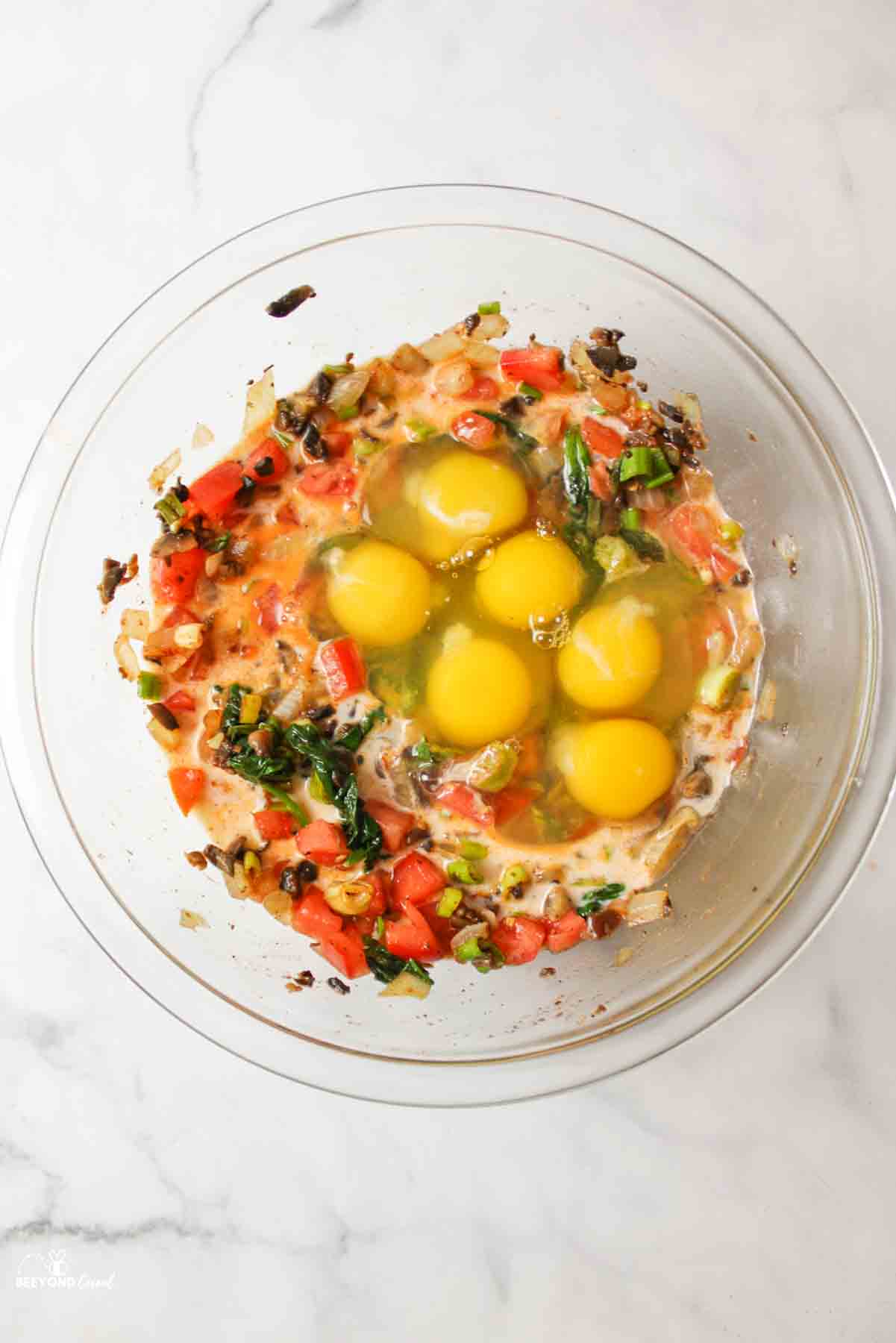 eggs and milk added to veggies in a bowl.