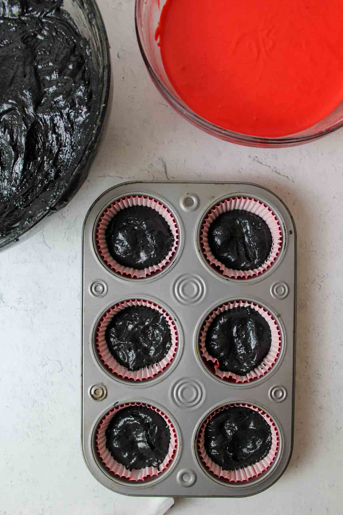 black cupcake batter in bottom of lined muffin tin.