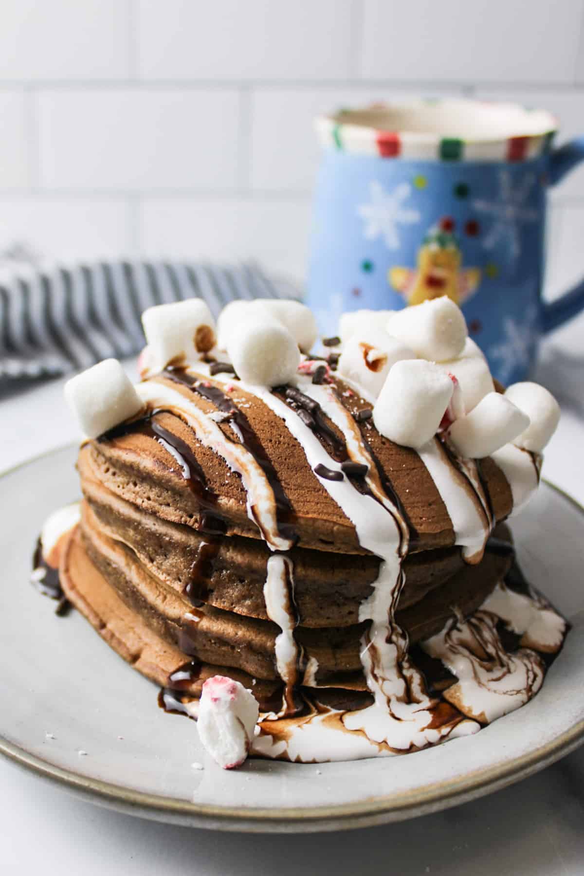 stack of hot chocolate pancakes on a plate topped with marshmallows and chocolate